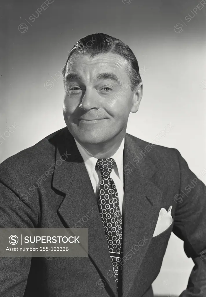 Vintage photograph. Man in suit and tie smiling at camera eyebrows raised.