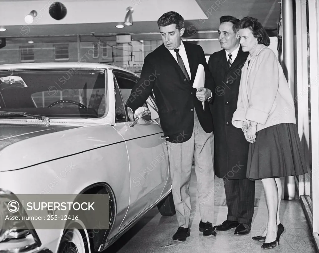 Close-up of a salesman showing a car to a mature couple