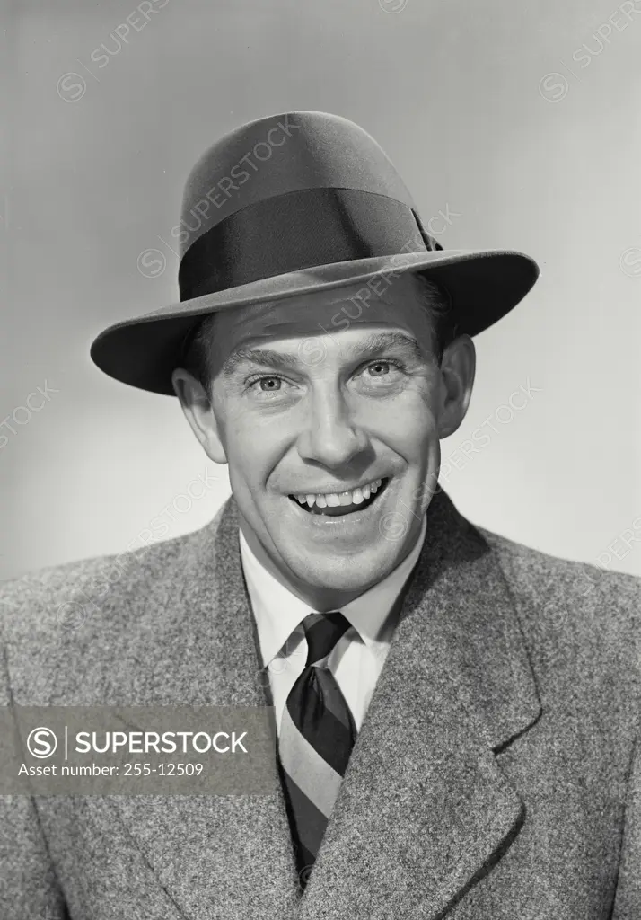 Vintage photograph. Portrait of Man in suit and tie wearing hat smiling wide at camera