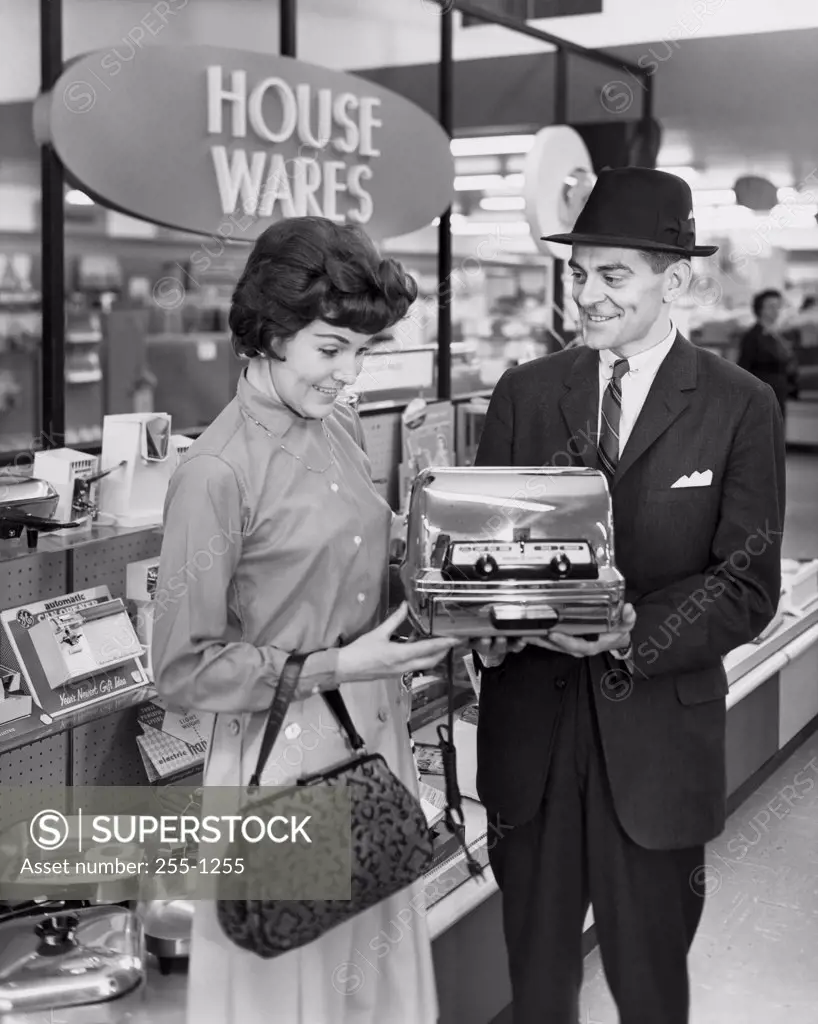 Mid adult man showing a toaster to a mid adult woman