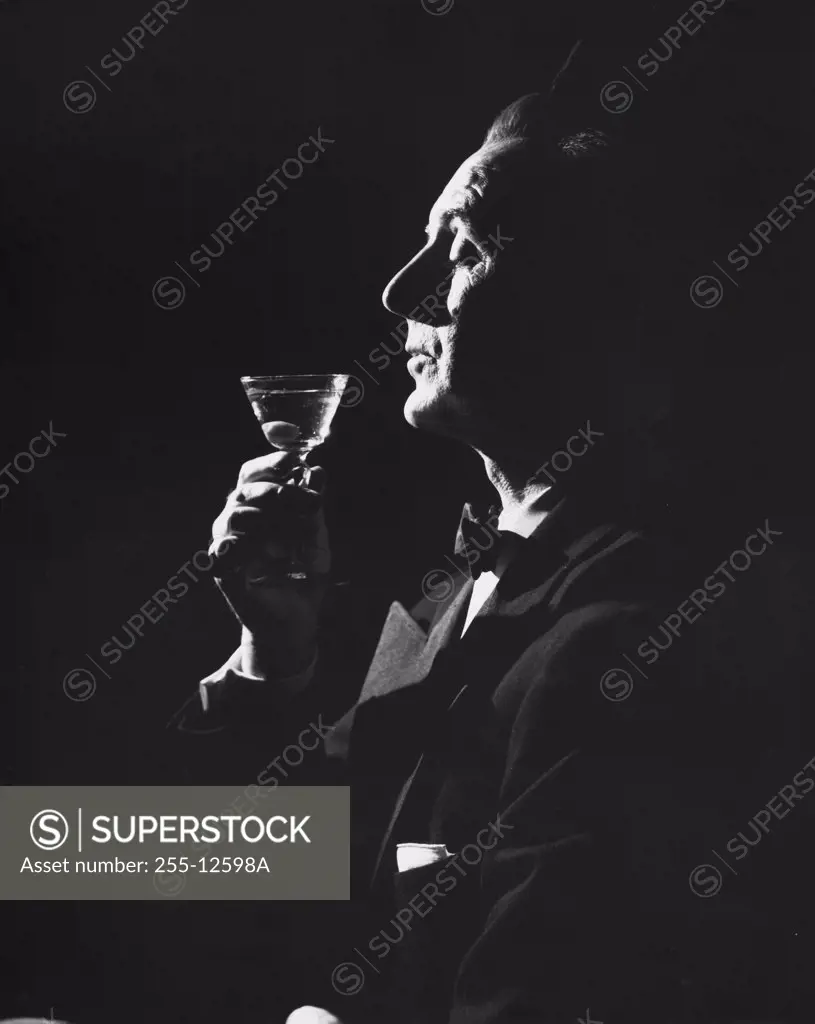 Side profile of a mature man holding a martini