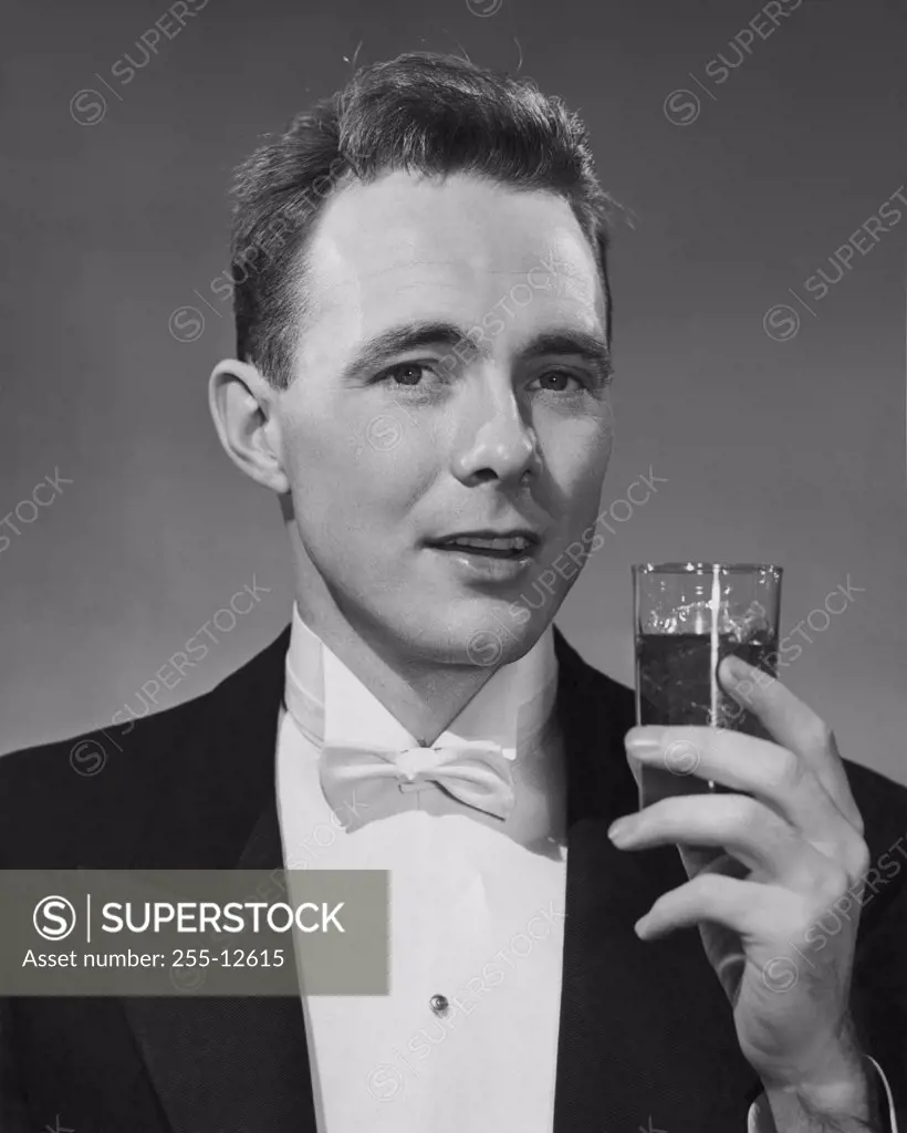 Vintage Photograph. Portrait of man in tuxedo holding small glass