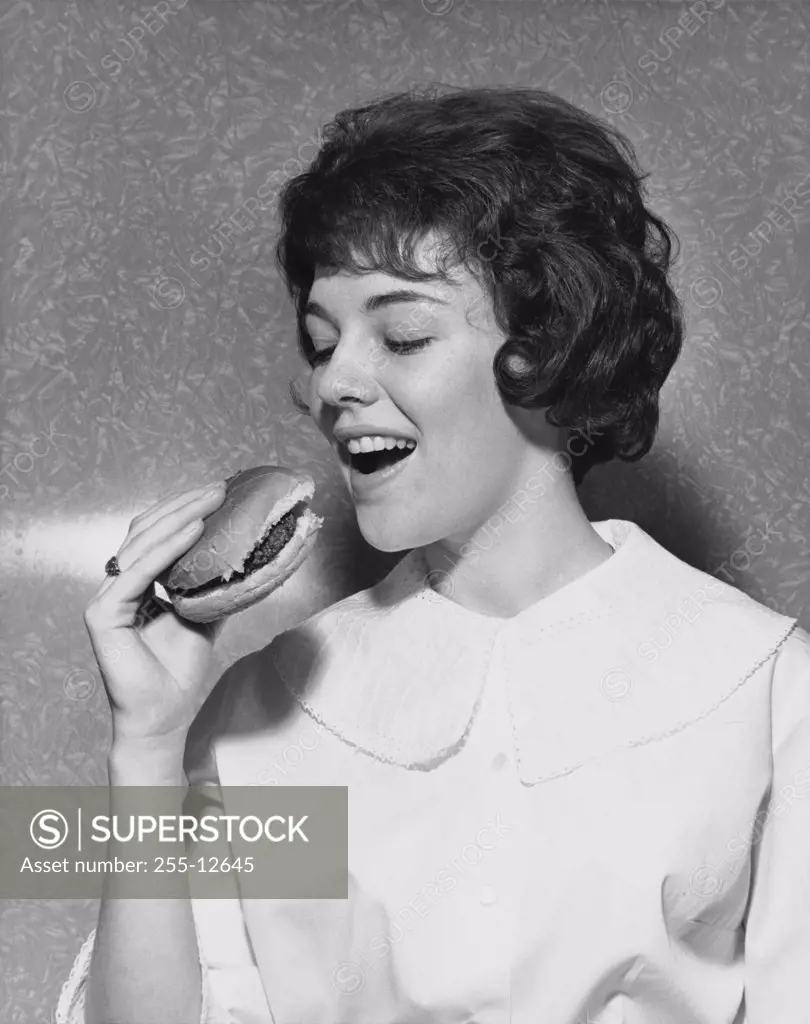 Close-up of a young woman eating a hamburger
