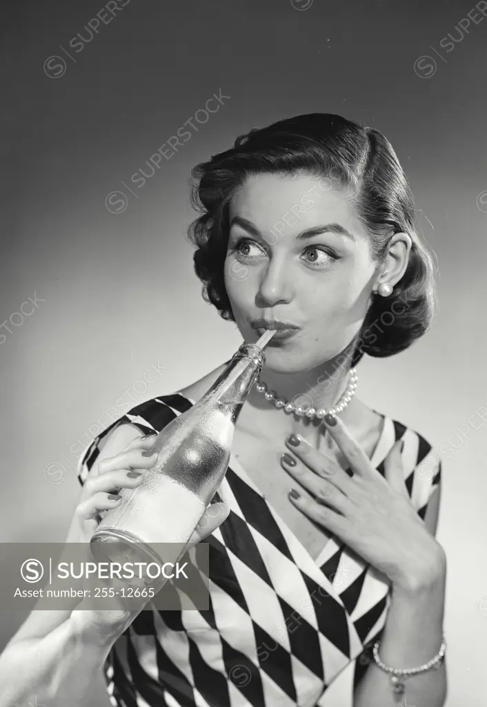 Vintage Photograph. Model in checkered blouse sipping drink through straw