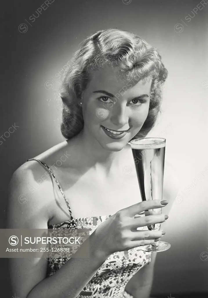 Woman in dress holding up glass and smiling