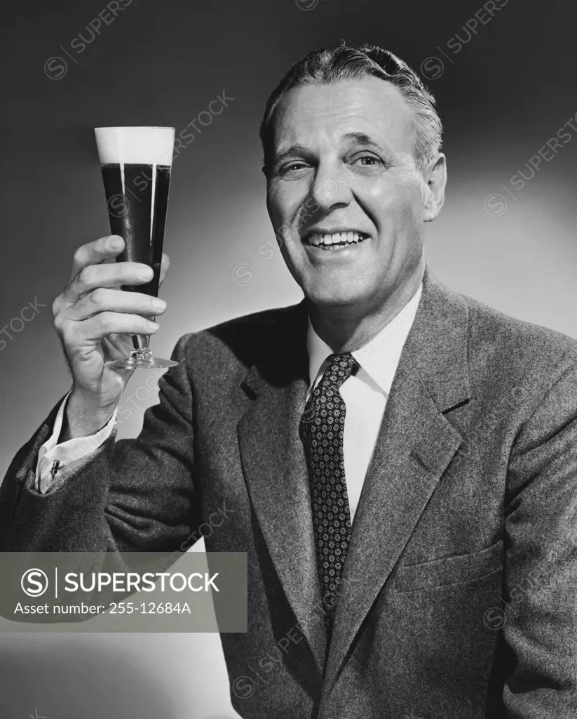 Studio portrait of mature man holding glass of beer