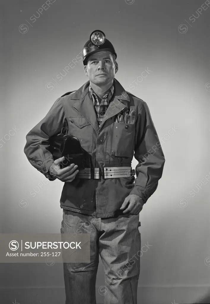 Working man in miners helmet and work clothes holding lunchbox