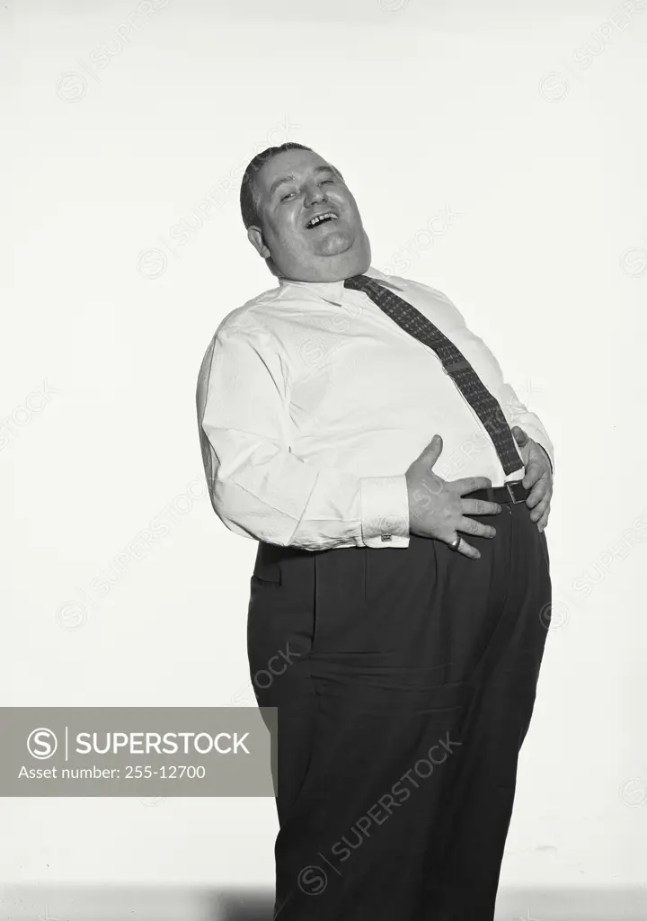 Vintage Photograph. Fat man wearing dress shirt and tie with hearty laugh holding stomach