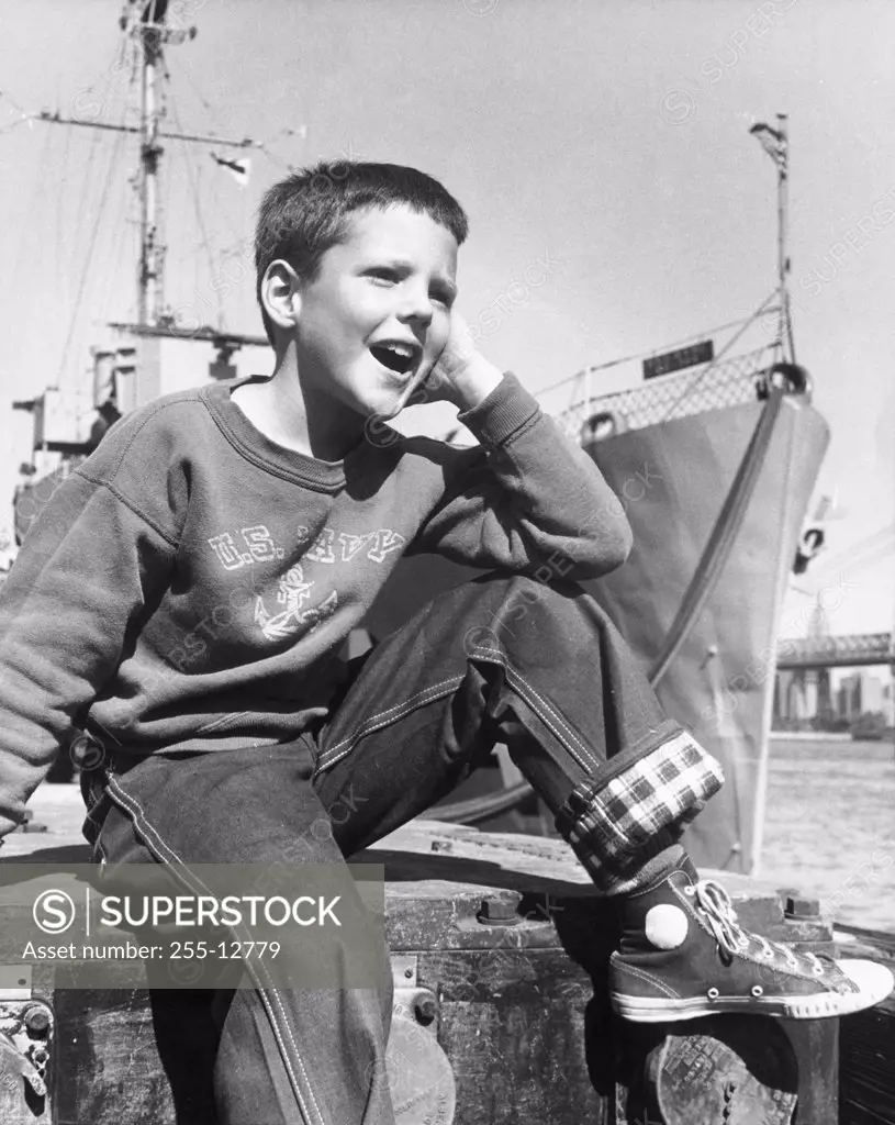 Boy sitting at a harbor