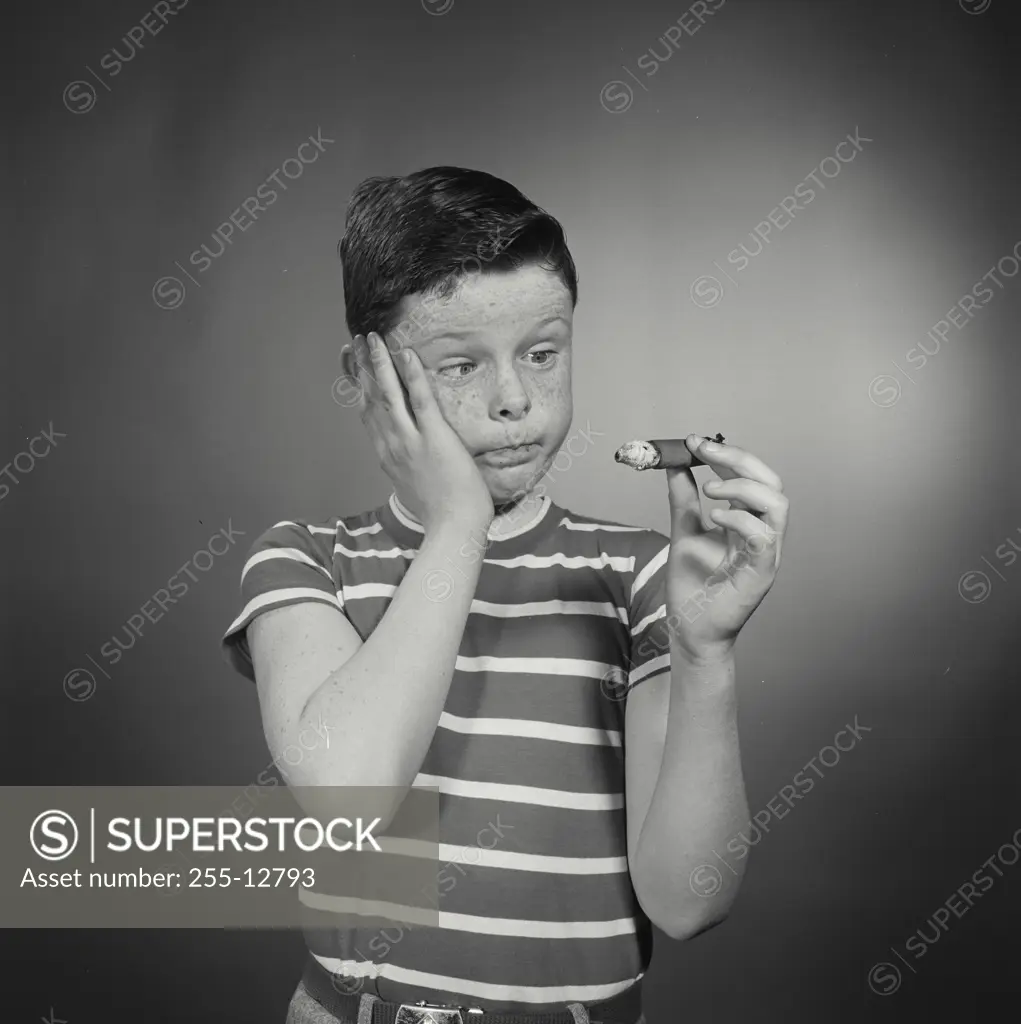 Vintage Photograph. Boy with shocked face holding large cigar.
