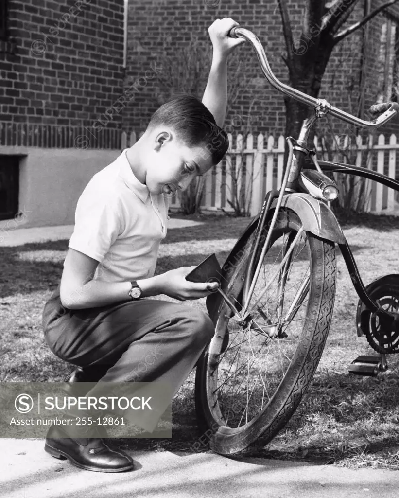 Boy oiling a bicycle