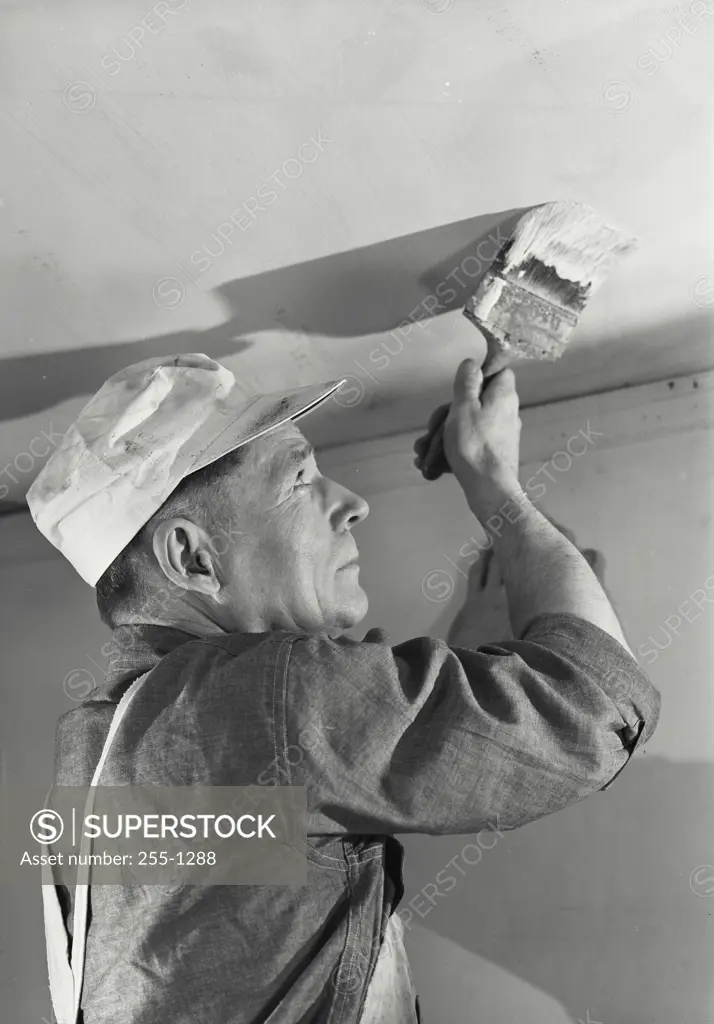 Vintage Photograph. Carpenter with a brush painting on ceiling