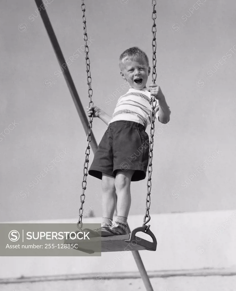 Boy standing on a swing and screaming