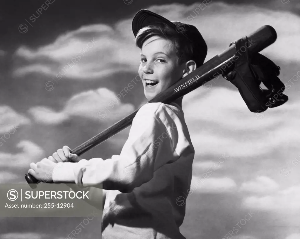Side profile of a boy carrying a baseball bat and baseball glove on his shoulder