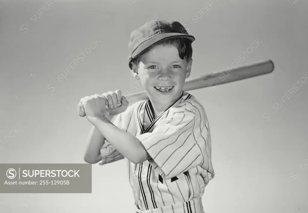 Vintage Photograph. Young boy wearing baseball uniform holding bat over shoulder