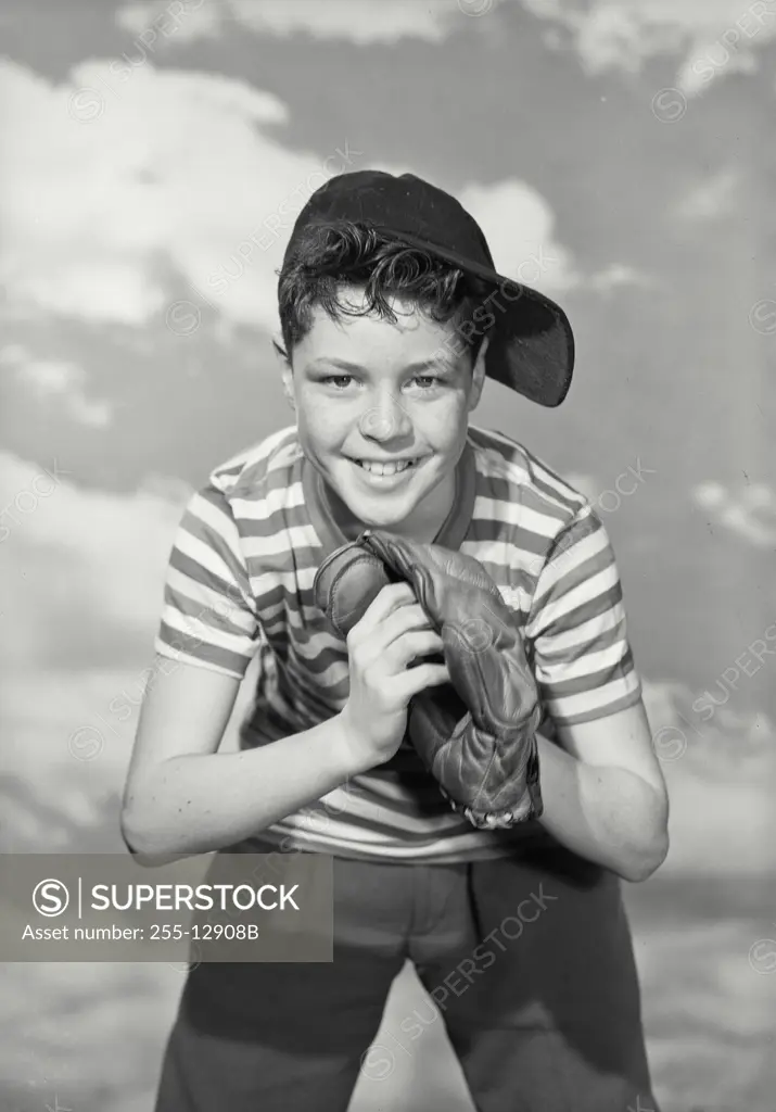 Vintage Photograph. Smiling boy in striped tee shirt and sideways ball cap wearing a baseball glove.