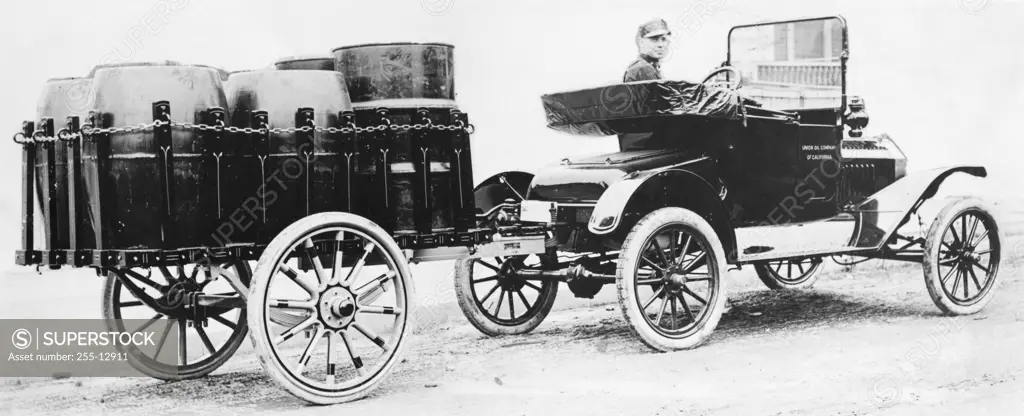 Rear view of a milkman driving a car attached with a vehicle trailer