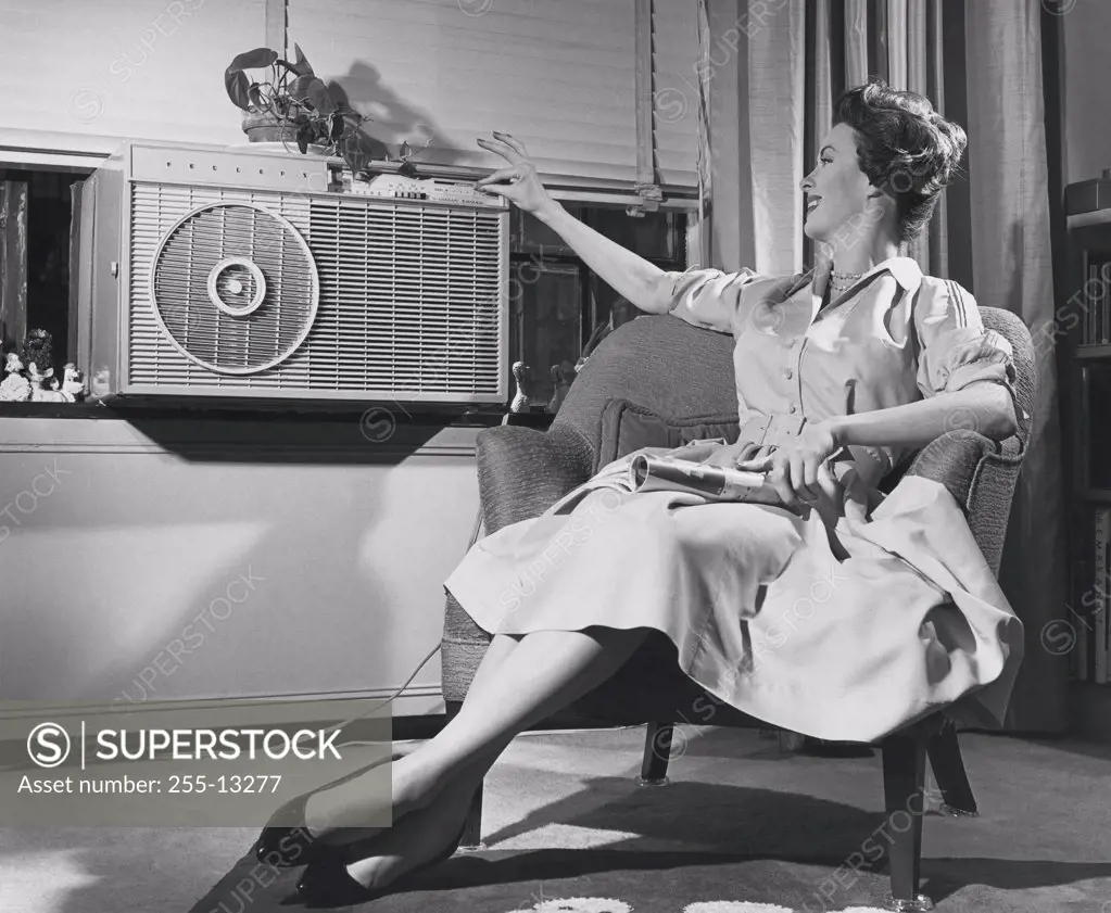 Young woman operating air conditioner