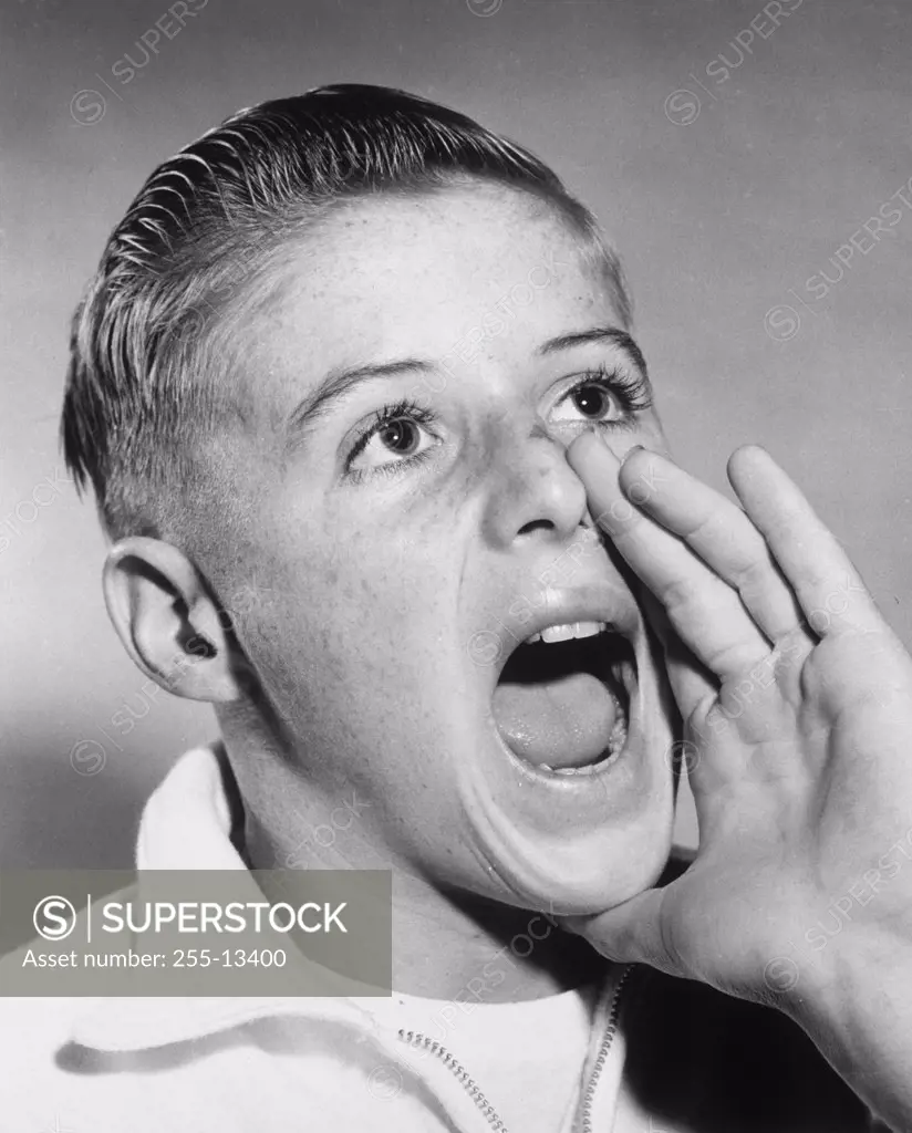 Close-up of a boy shouting with his hand near his mouth