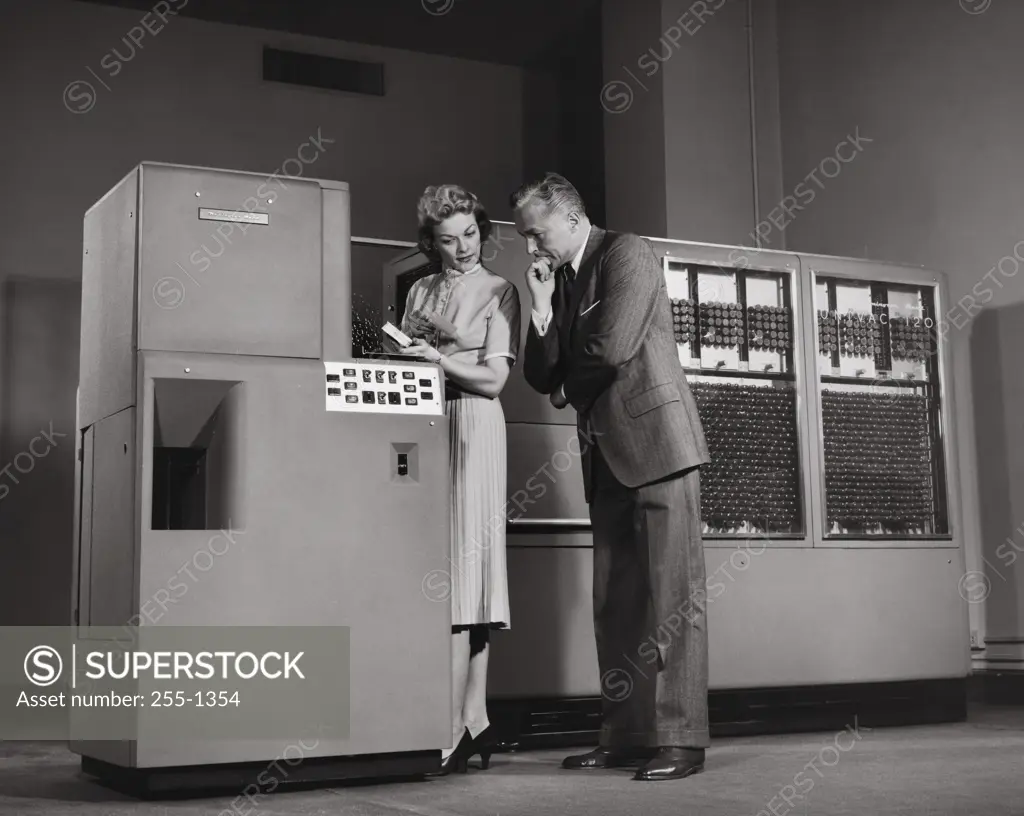 Side profile of businessman and his secretary working on computer, Univac 120