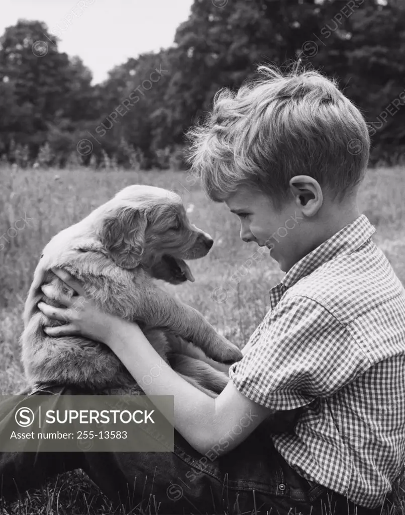 Side profile of boy holding his puppy