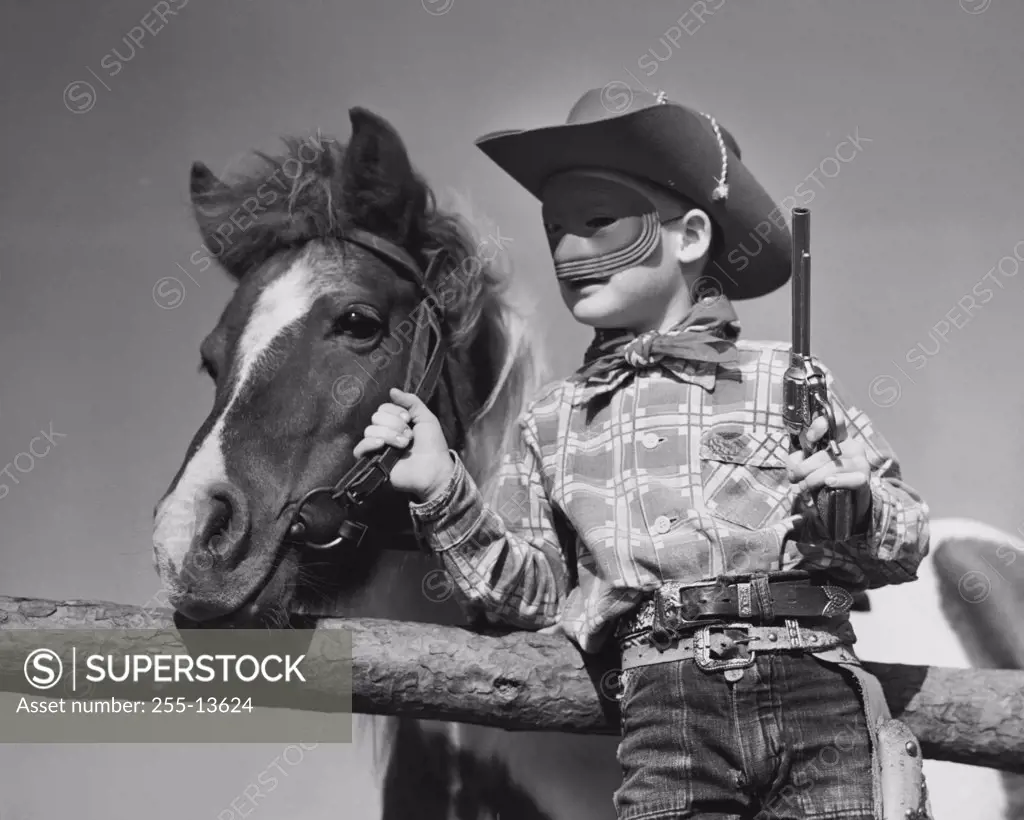 Low angle view of boy in cowboy costume standing with horse