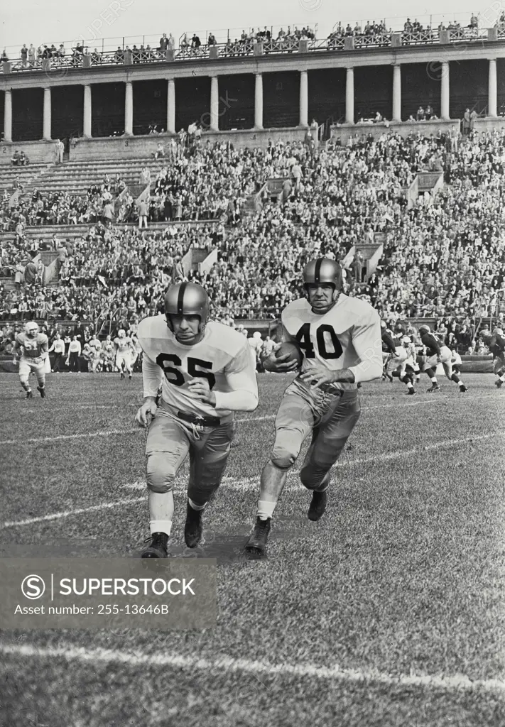Vintage Photograph. Two football players running on field towards camera.