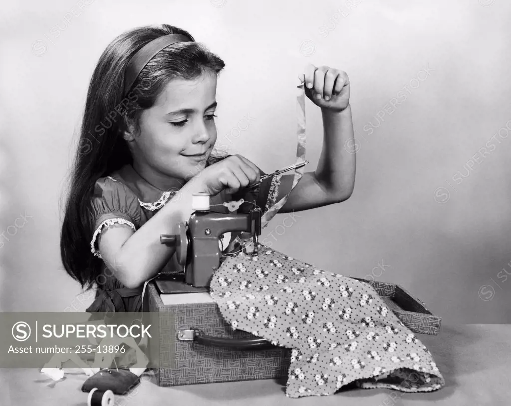 Girl sewing clothes with a toy sewing machine