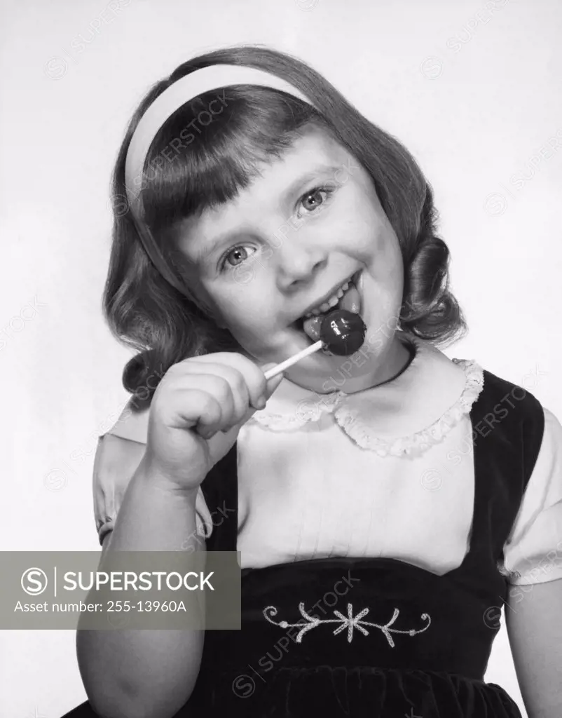Portrait of a girl licking a lollipop
