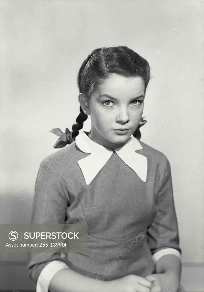 Vintage Photograph. Girl with pigtails wearing dress looking at camera