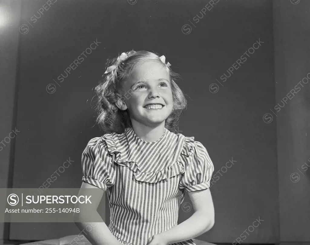 Vintage photograph. Close-up of a smiling little girl wearing a striped dress