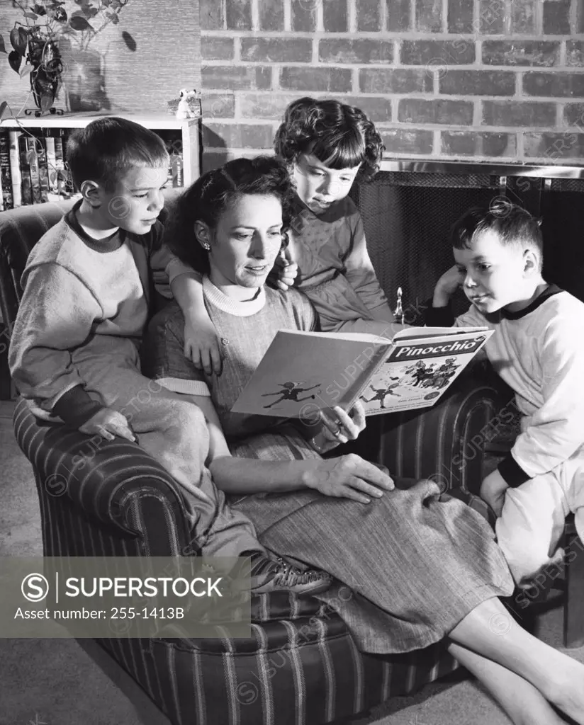 Close-up of a mid adult woman reading a storybook with her son and daughter