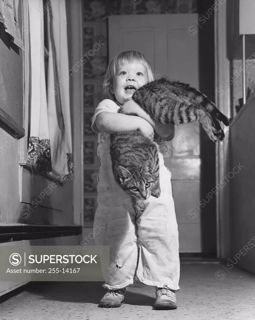 Child holding cat in house