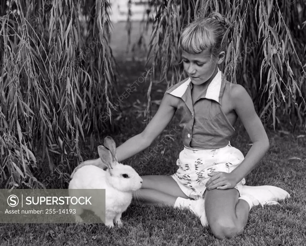 Girl playing with rabbit on lawn in garden