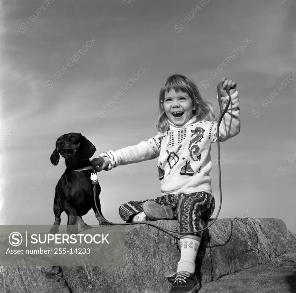 Girl with dog sitting on rock