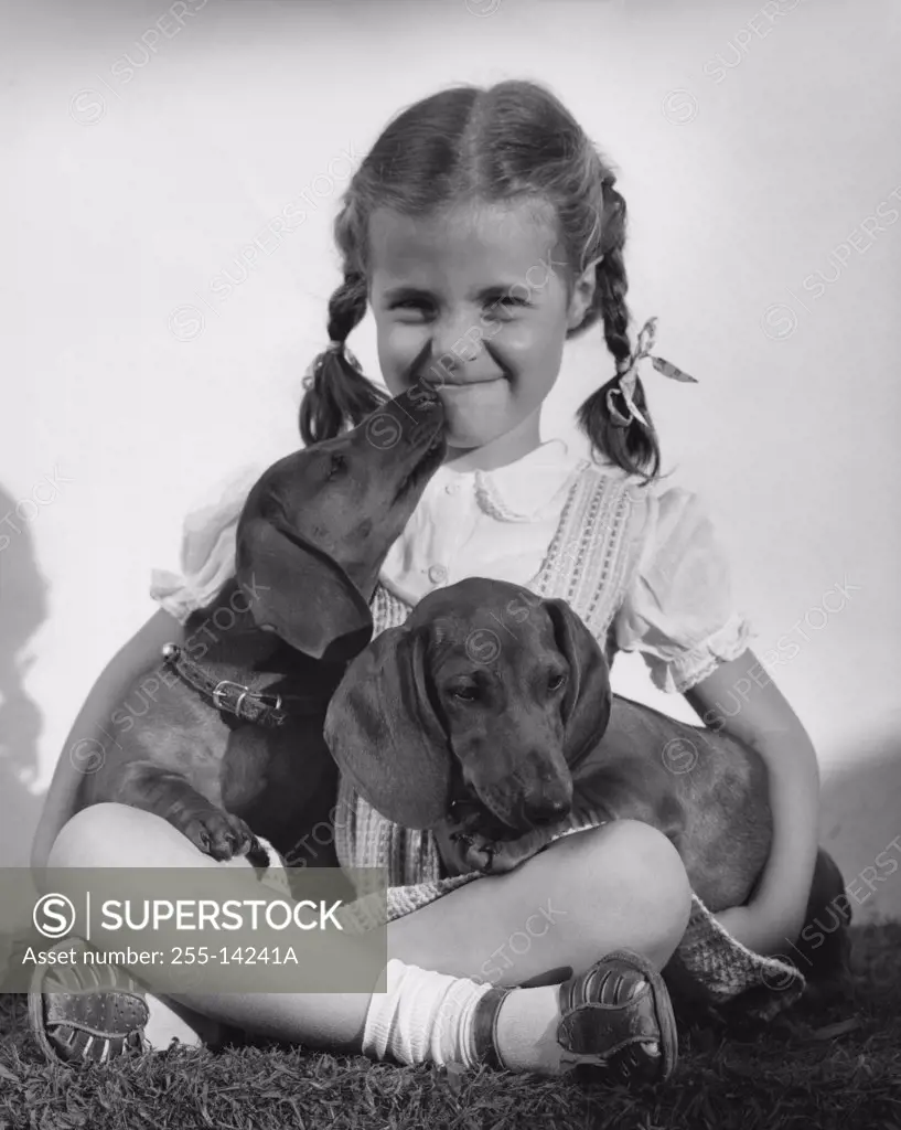Close-up of a girl sitting and holding two Dachshund puppies