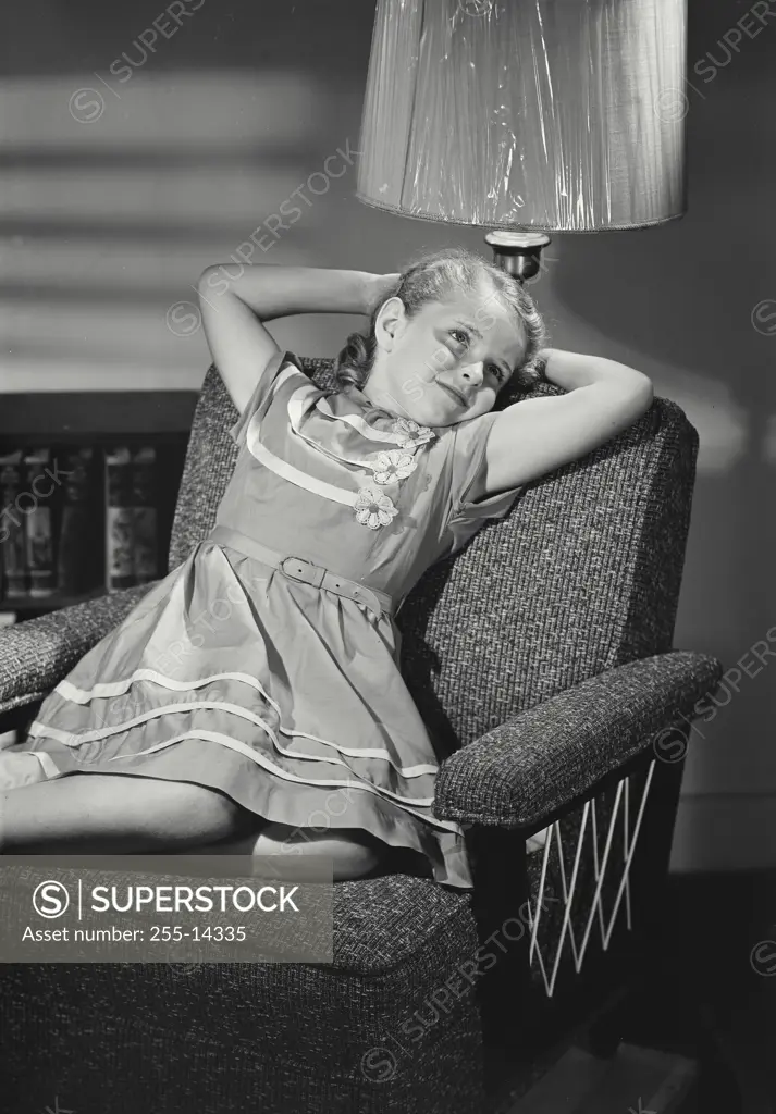 Vintage Photograph. Young girl in dress laying on chair