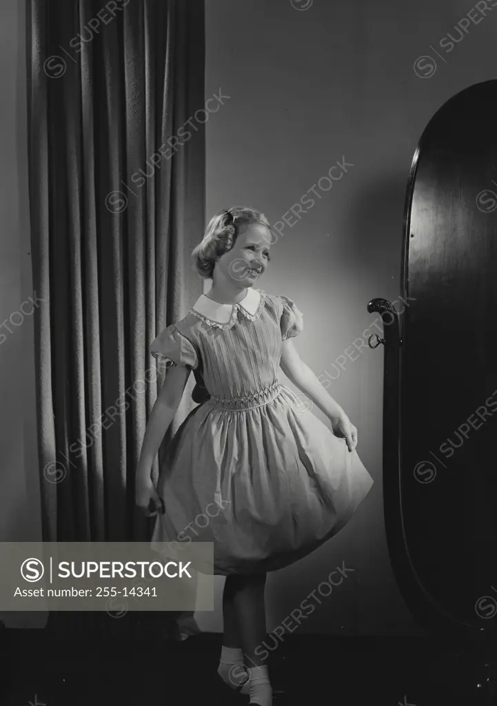 Vintage Photograph. Young girl wearing dress posing in mirror