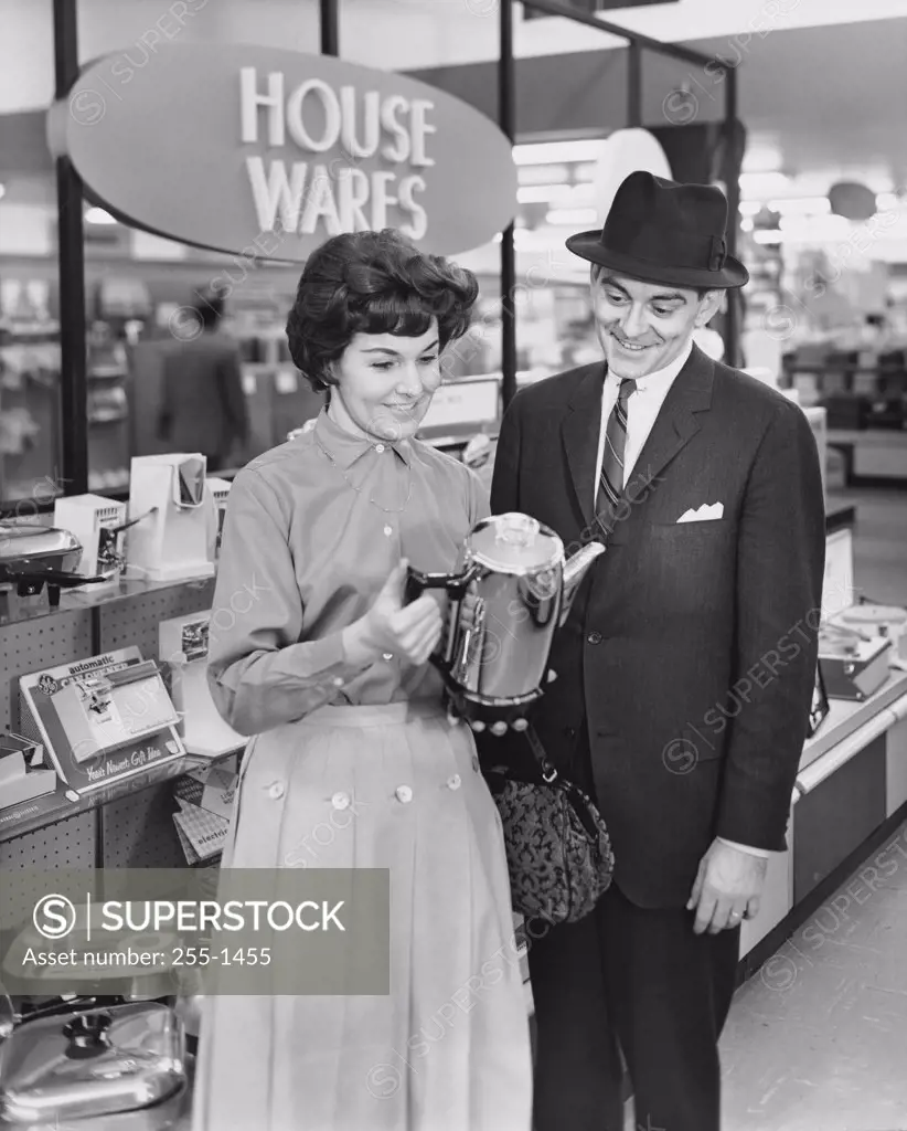 Mid adult woman and a mature man looking at a kettle in a store