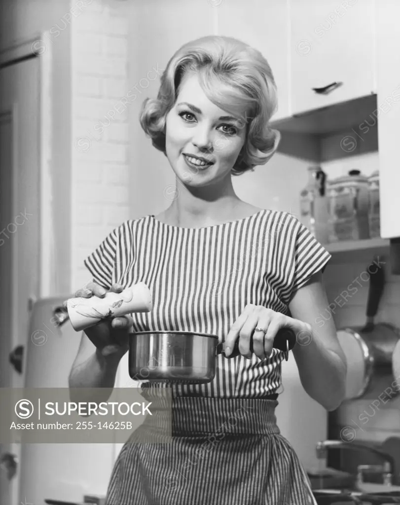 Young woman holding a pan and smiling