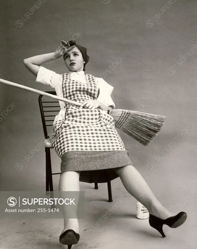 Young woman sitting in a chair holding a broom