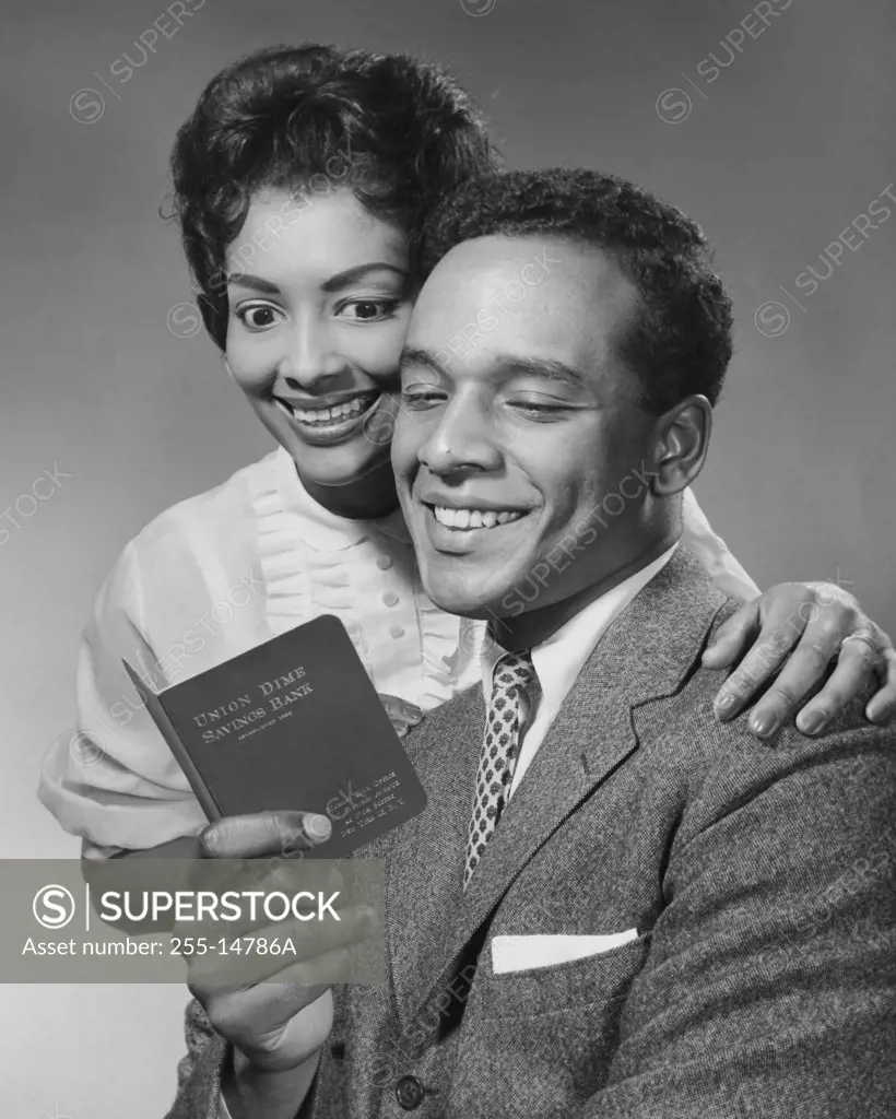 Close-up of a young couple looking at a bankbook and smiling