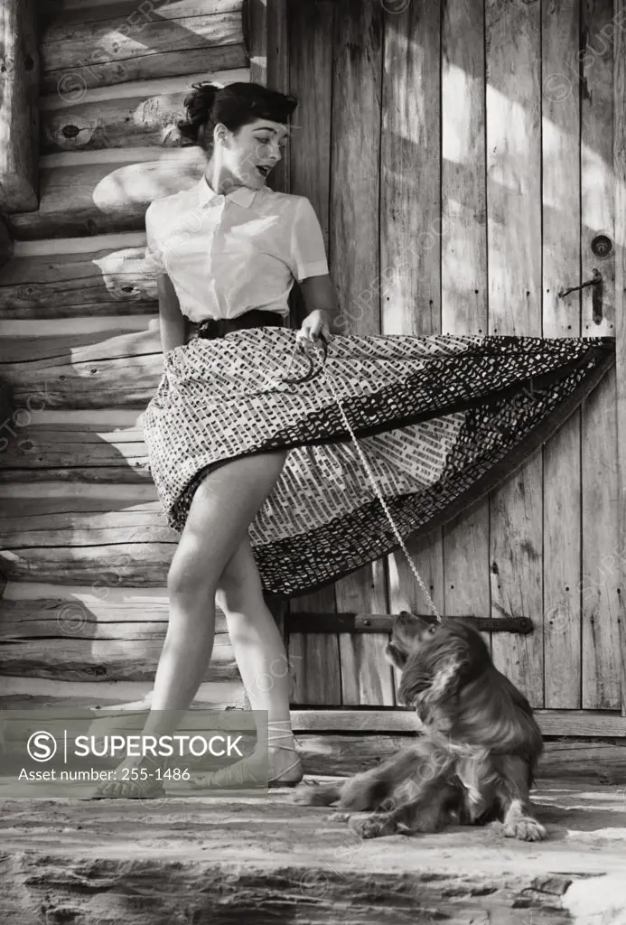 Young woman standing in front of her house with her dog