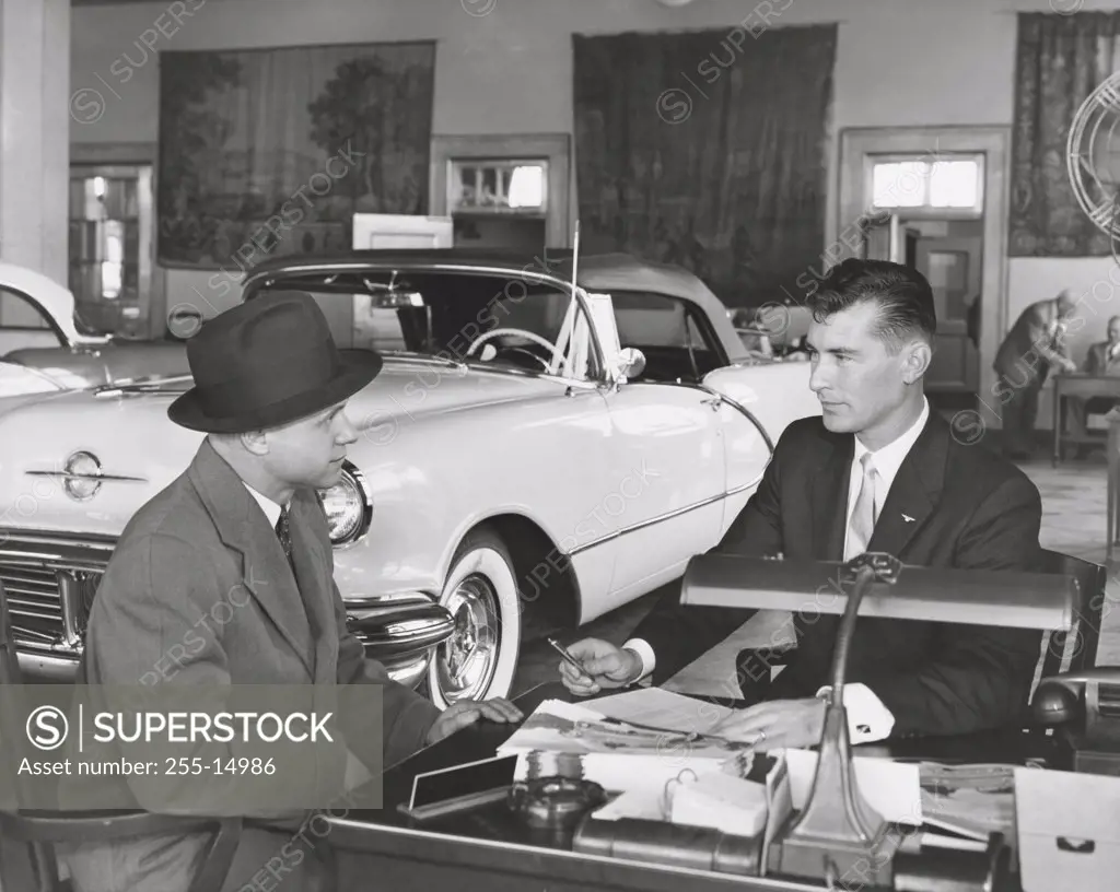 Mid adult man buying a car from a salesperson
