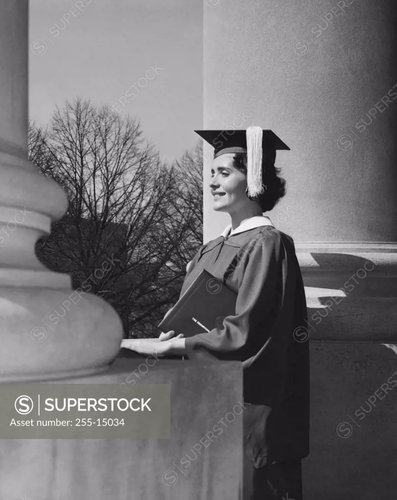 Side profile of a young woman dressed in a graduation gown, smiling