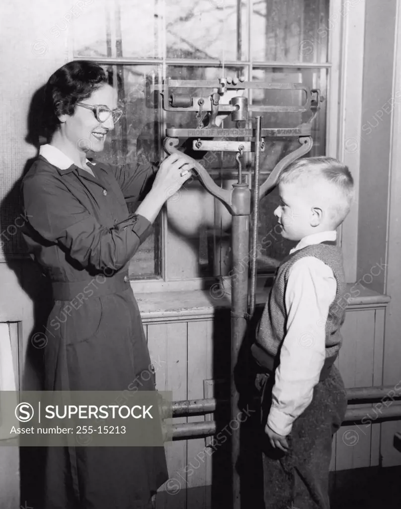 Side profile of a female pediatrician weighing a boy