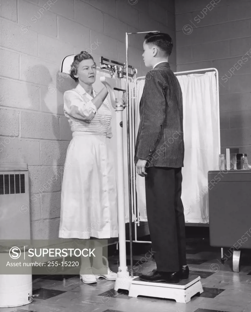 Female nurse measuring height and weight of a boy