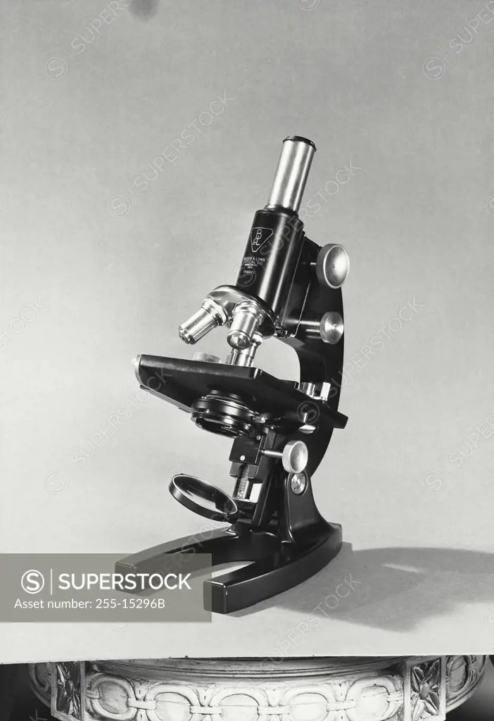 Vintage Photograph. Bausch and Lomb Microscope sitting on solid light background, viewed from left side at an angle