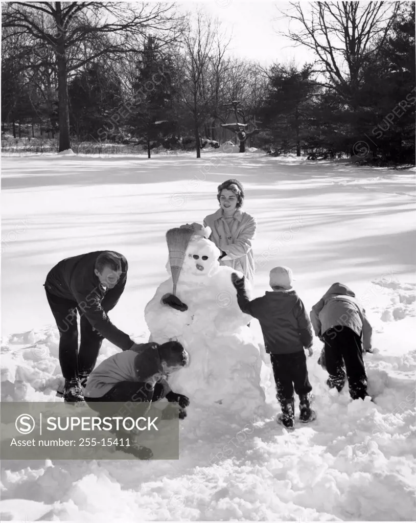 High angle view of parents and their three children making a snowman