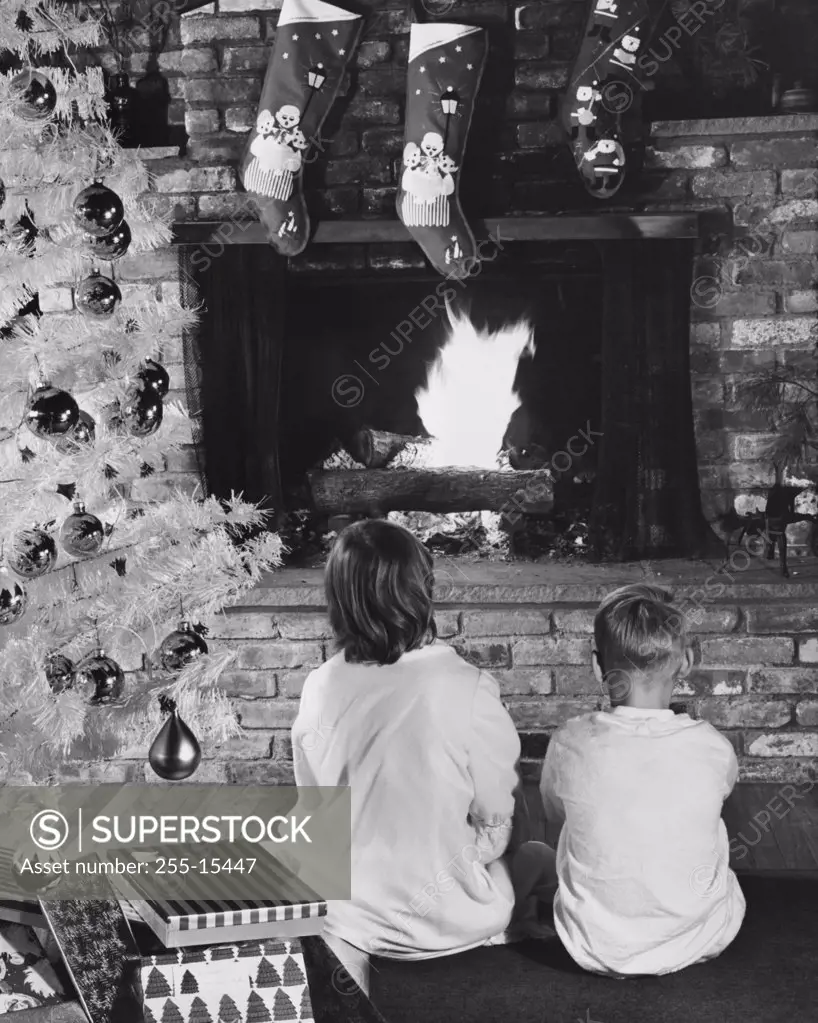 Rear view of two boys sitting near fireplace